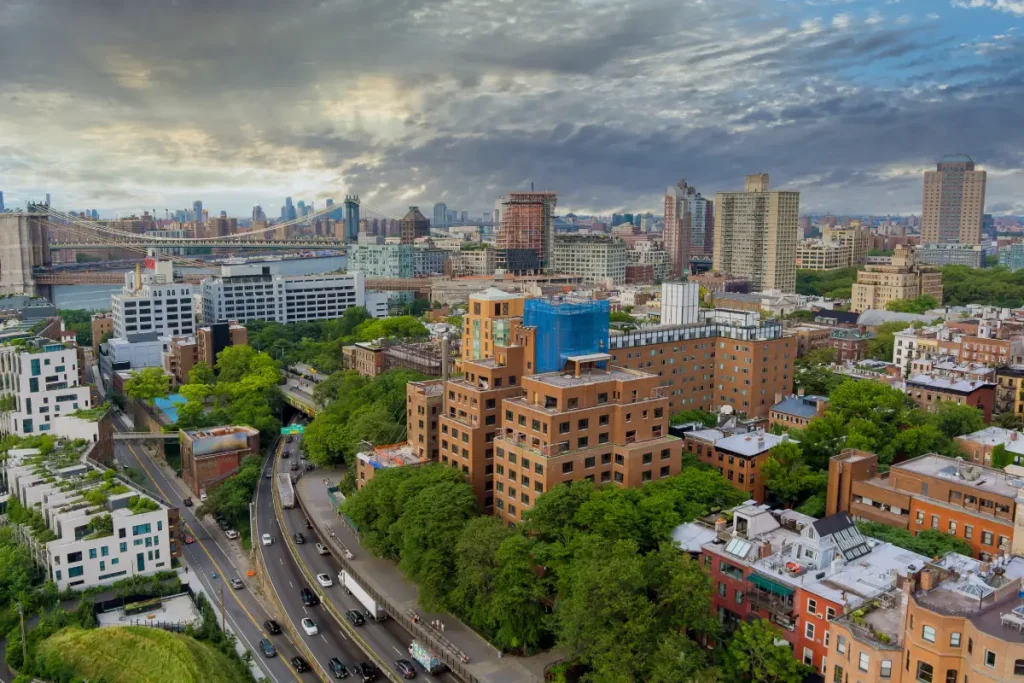 A vibrant Brooklyn NYC skyline featuring numerous buildings and a prominent bridge against a clear blue sky
