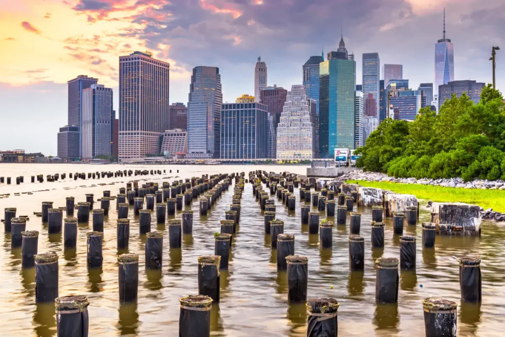 Manhattan skyline viewed from the water, showcasing iconic skyscrapers against a clear blue sky